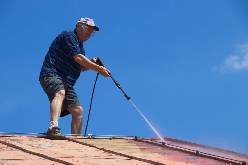 homeowner pow3er washing a metal roof as routine maintenance or prior to paint