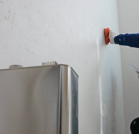 Scraping the adhesive off the wall.